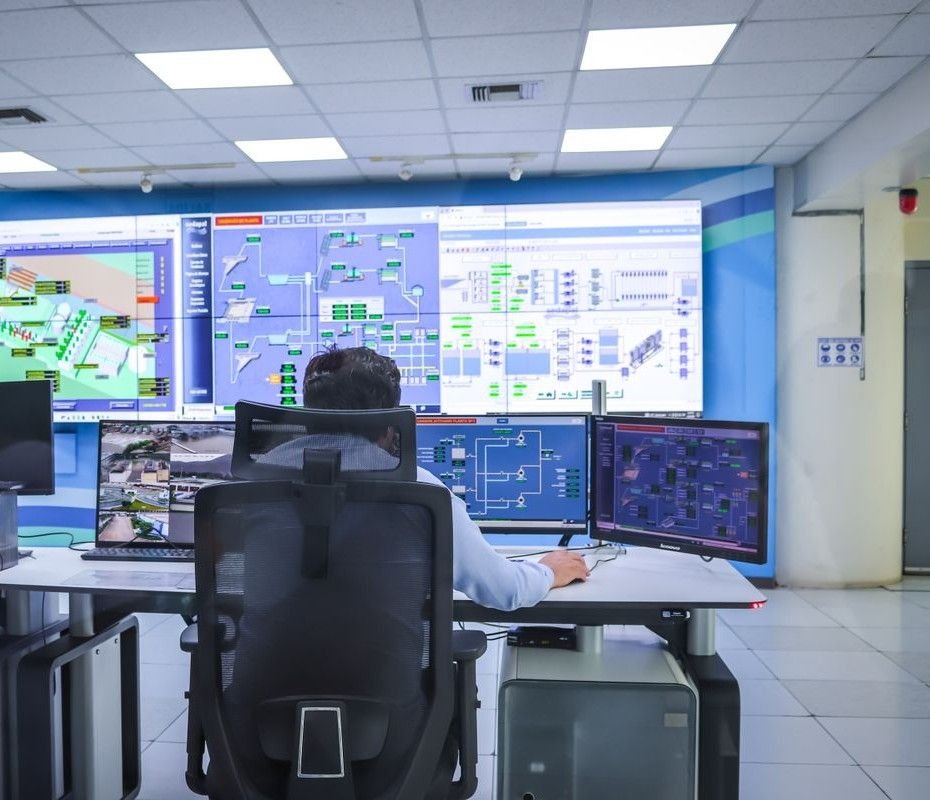 Operador em sala de controle moderna acompanhando o processo em telas de supervisório