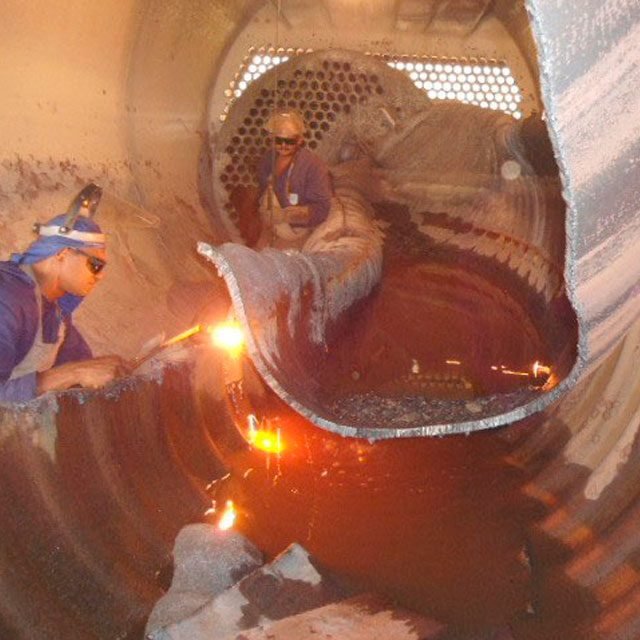 Técnicos cortando e soldando dentro de uma caldeira
